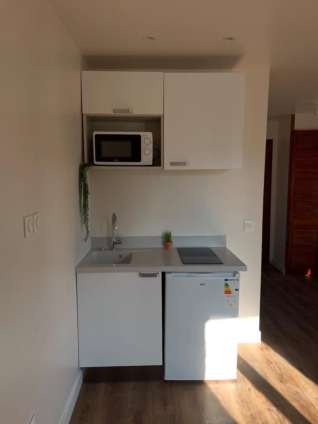 Kitchenette blanche dans un studio locatif renove